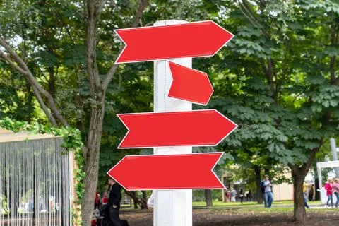 Three red arrows point opposite directions on a white pole Stock Photos