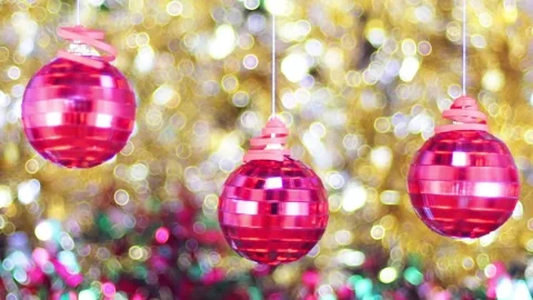 Three red balls spinning on strings against a background of golden tinsel Stock Footage 139138546