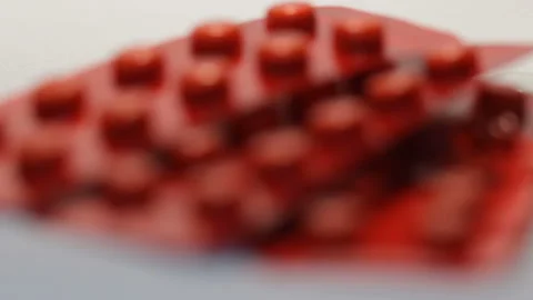 Three red blisters of same small round pills on the table in focus in studio 스톡 동영상 86563104