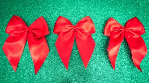 Three red bows on a green background. Stock Photos