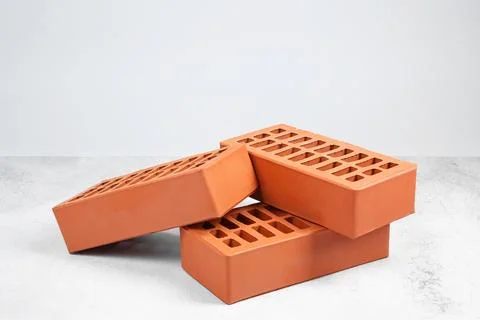 Three red bricks on textured table against light background. Building materia Stock Photos