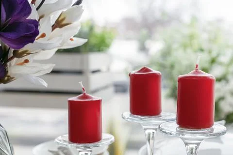 Three red candles on the background of the window Foto stock