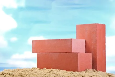 Three red ceramic bricks on the sand at the blue sky background Stock Photos
