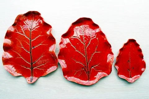 Three red ceramic plates with leaf imprint glossy glaze Stock Photos