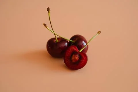 Three red cherries on peach background Stock Photos
