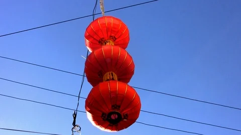 Three red Chinese lanterns one above the other blown by the wind Stock Footage 107482185