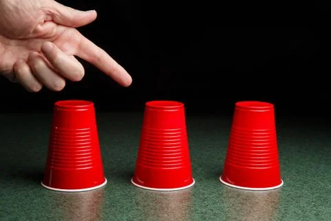 Three red cups and a pointing hand Stock Photos