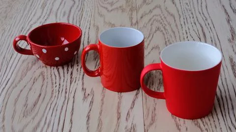 Three red cups of different shapes standing in a row one after another throug Stock Photos