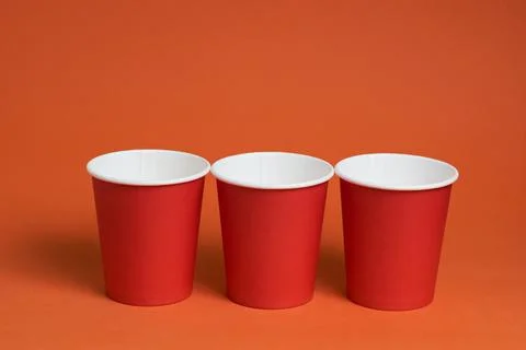 Three red disposable cups on a brown background. Place for text Stock Photos