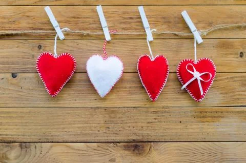 Three red felt hearts and one white. symbol for a family, love. On wooden Stock Photos