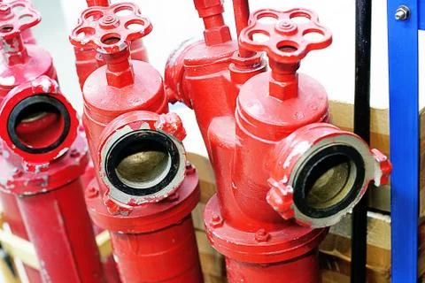 Three red fire hydrants with valves are in the warehouse Foto stock