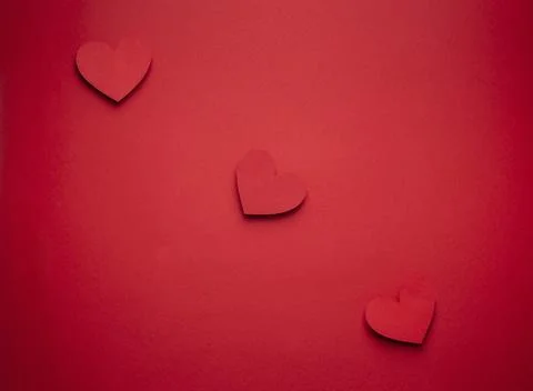 Three red hearts in a row cut from paper on red background, craft origami style, 스톡 사진
