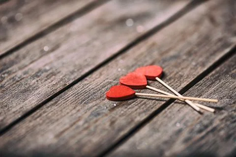 Three red hearts shape on stick over wooden background. Valentine concept Fotos Stock
