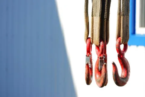 Three red hooks hanging from belts in bright sunlight. Stock Photos