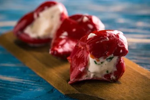 Three red pepper filled by cheese on wooden spoon Stock Photos