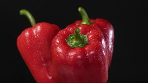 Three red peppers in drops of water on a black background rotate Video stock 157798135