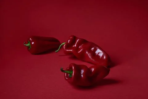 Three red peppers on a red background Stock Photos
