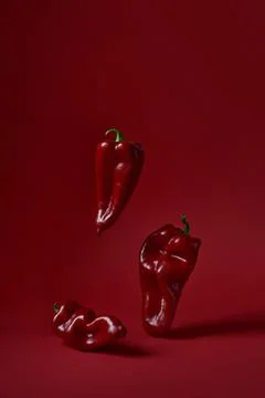 Three red peppers on a red background Stock Photos
