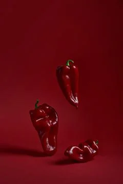 Three red peppers on a red background Stock Photos