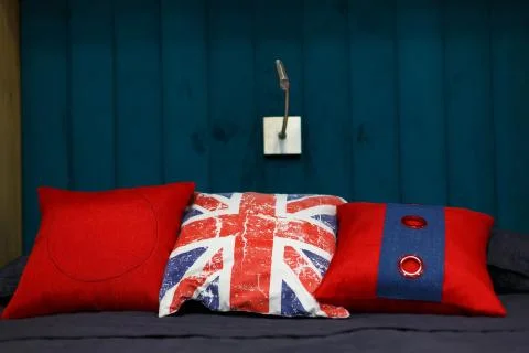 Three red pillows lie on the bed. Pillows an English flag. Stock Photos