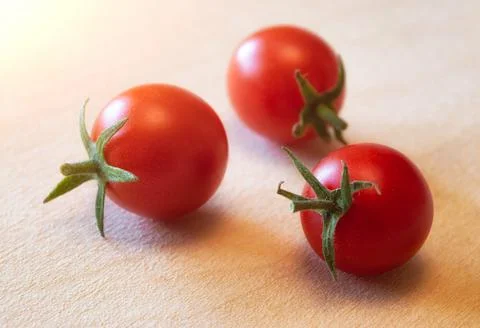 Three red ripe small cherry tomatoes in the sun Stock Photos