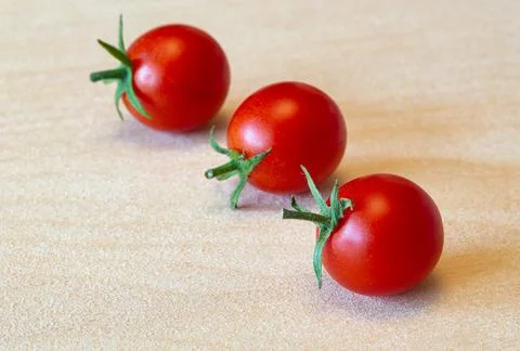Three red ripe small cherry tomatoes on wood texture Stock Photos