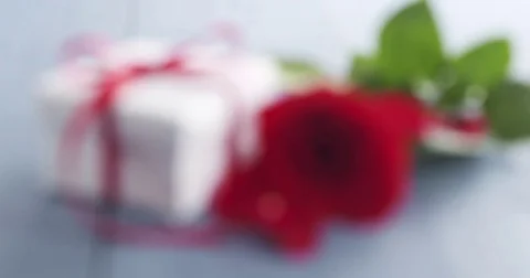 Three red roses with gift box on blue wood table focus pull Stock Footage 71927165