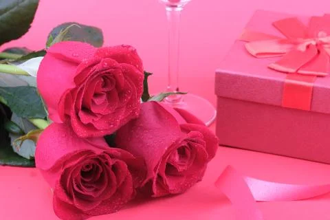 Three red roses on a red background with a box Stock Photos