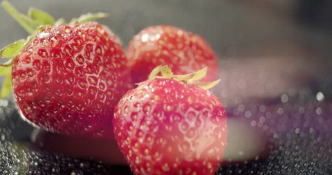 Three red strawberries with bokeh on dark background,seasonal local fresh berry Vídeo Stock 133587565