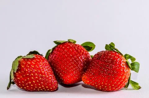 Three red strawberries on a white background Stock Photos