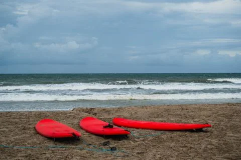 Three Red Surfboards on a Sandy Beach Near the Ocean Fotos de archivo