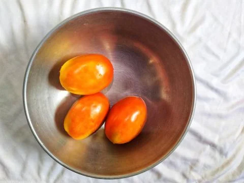 Three red tomatoes in hod pan on white background Stock Photos