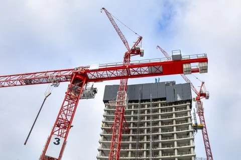 Three red tower cranes on skyscraper building construction site Stock Photos