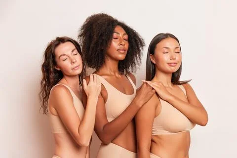 Three representatives of different races pose in the studio in underwear and Stock Photos