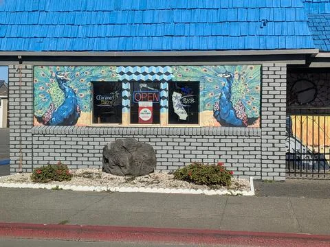 Three restaurant windows glow with Open and delivery signs Фото