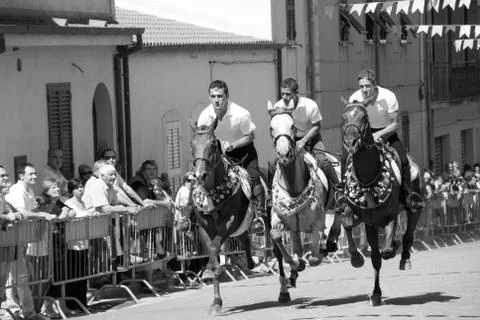 Three riders gallop parade through the street of a village Stock Photos