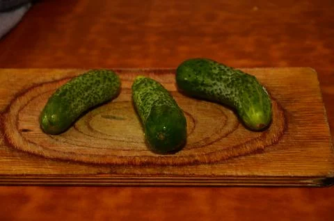 Three ripe cucumbers on a light background of a cutting board Stock Photos