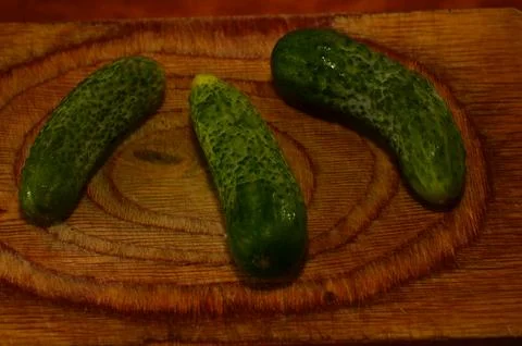 Three ripe cucumbers on a light background of a cutting board Stock Photos