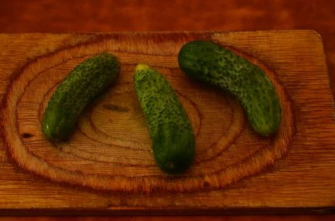 Three ripe cucumbers on a light background of a cutting board Stock Photos