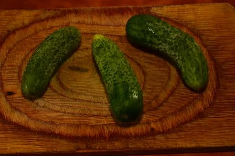 Three ripe cucumbers on a light background of a cutting board Stock Photos