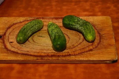 Three ripe cucumbers on a light background of a cutting board Stock Photos