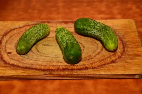 Three ripe cucumbers on a light background of a cutting board Stock Photos