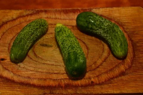 Three ripe cucumbers on a light background of a cutting board Stock Photos