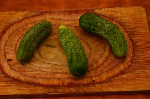 Three ripe cucumbers on a light background of a cutting board Stock Photos