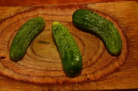 Three ripe cucumbers on a light background of a cutting board Stock Photos
