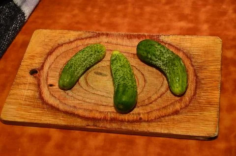 Three ripe cucumbers on a light background of a cutting board Stock Photos