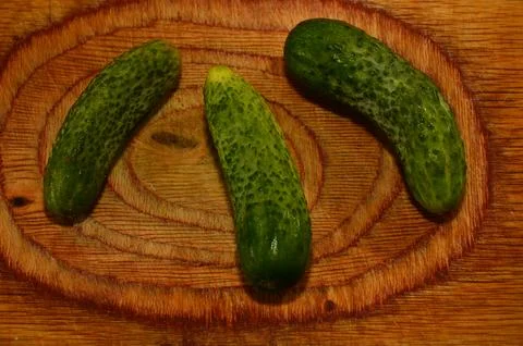 Three ripe cucumbers on a light background of a cutting board Stock Photos