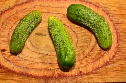 Three ripe cucumbers on a light background of a cutting board Stock Photos