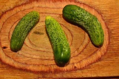 Three ripe cucumbers on a light background of a cutting board Stock Photos