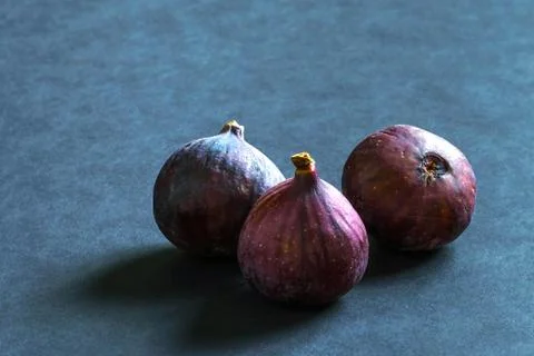 Three ripe figs on a gray background. Stock Photos